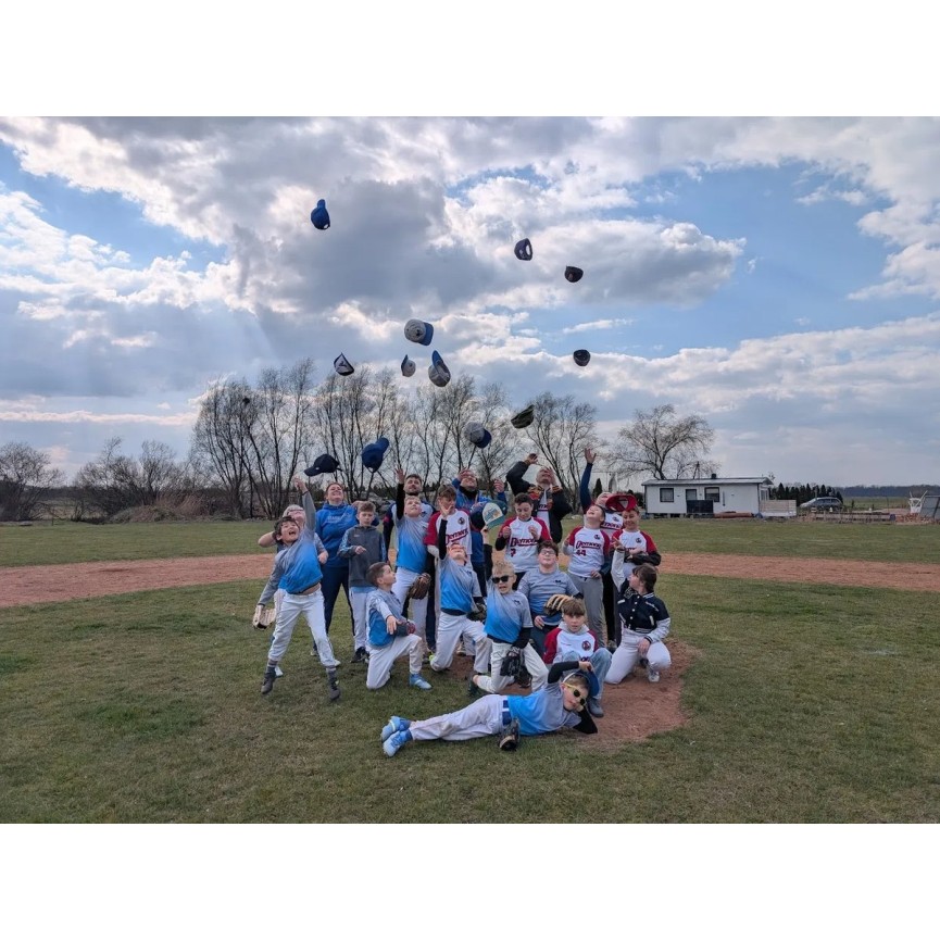 Goats Poznań — drużyna dzieci z czapkami rzuconymi w górę na boisku baseballowym